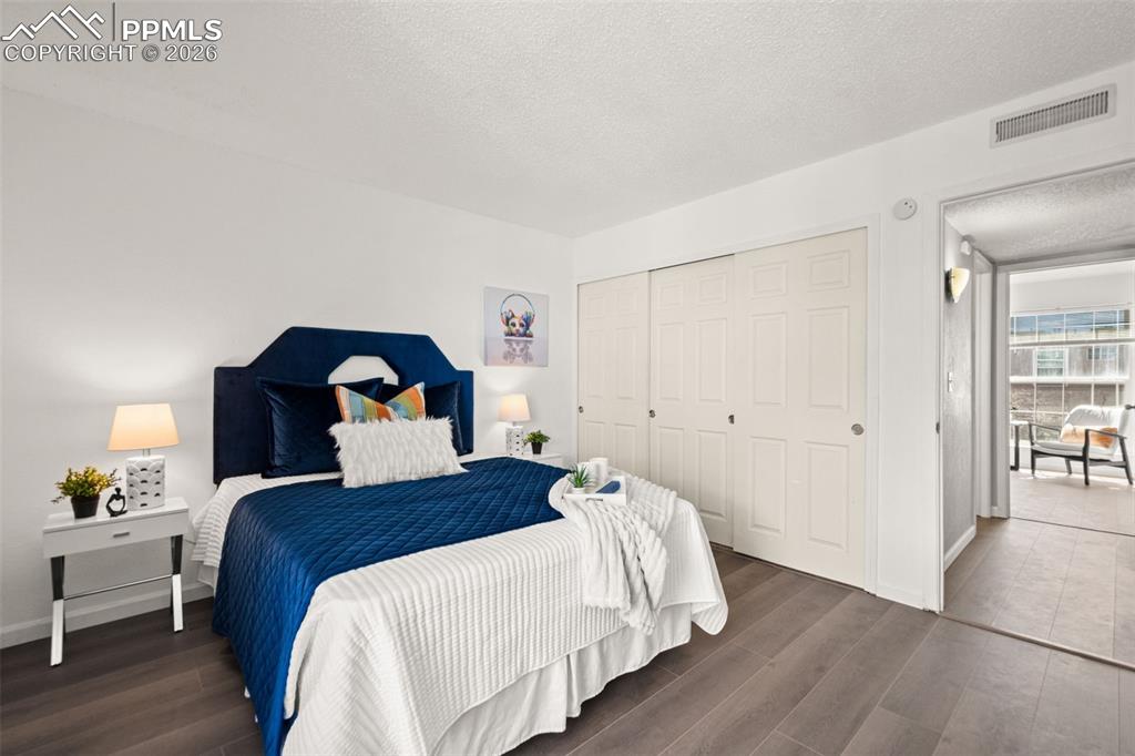 Image 22 of 27: Bedroom featuring dark wood-style flooring, a dark blue headboard, and whit