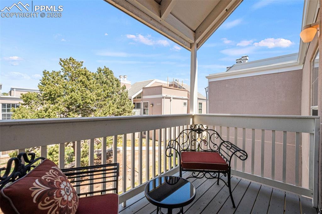 Image 25 of 27: The property features an outdoor balcony with a light-colored wood floor, a