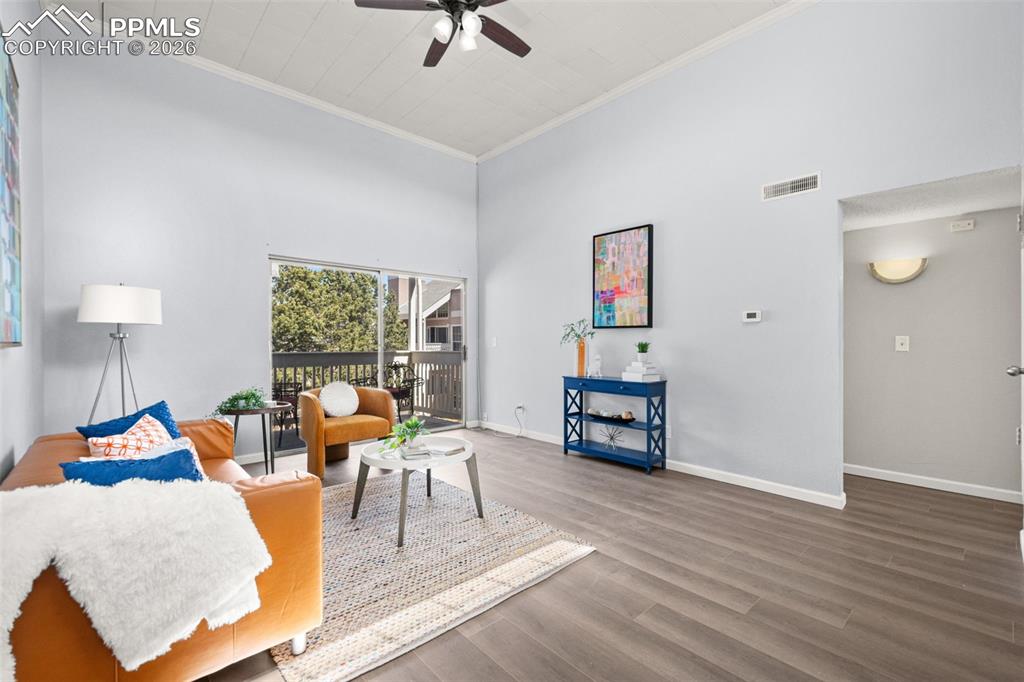 Image 6 of 27: The living area features vaulted ceilings, wood-look flooring, and sliding 