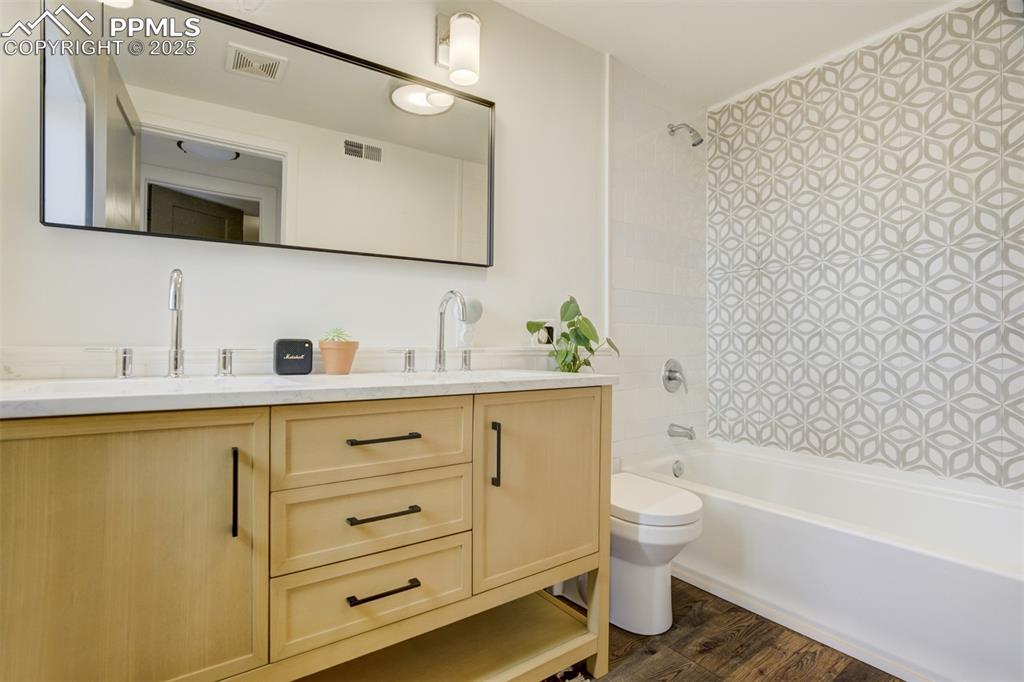 Image 26 of 35: Full bathroom in the basement with a new double-sink vanity.