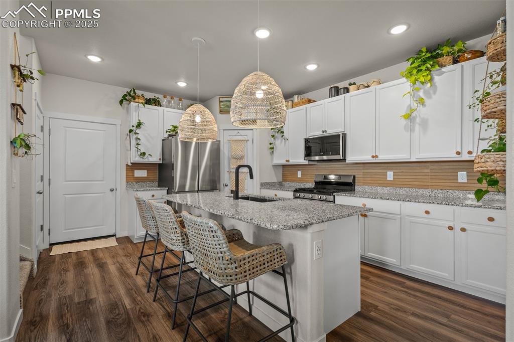 Image 14 of 49: Kitchen featuring a sink, stainless steel appliances, backsplash, a breakfa