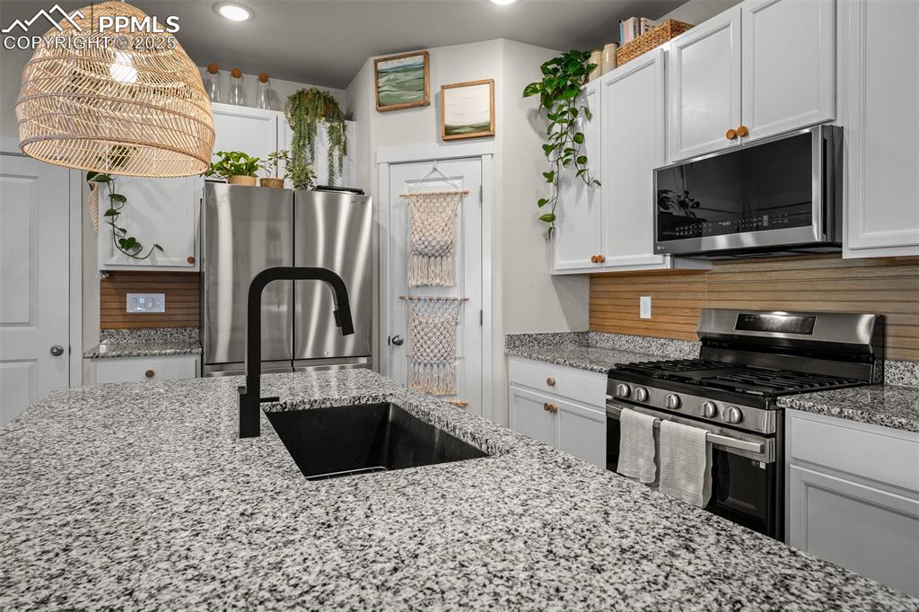 Image 15 of 49: Kitchen featuring appliances with stainless steel finishes, a sink, white c
