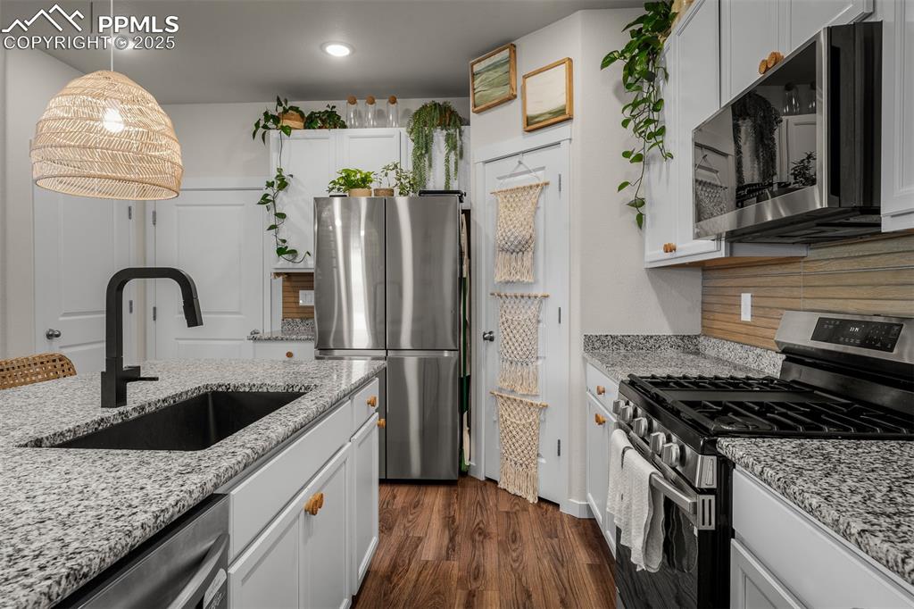 Image 16 of 49: Kitchen featuring appliances with stainless steel finishes, a sink, dark wo