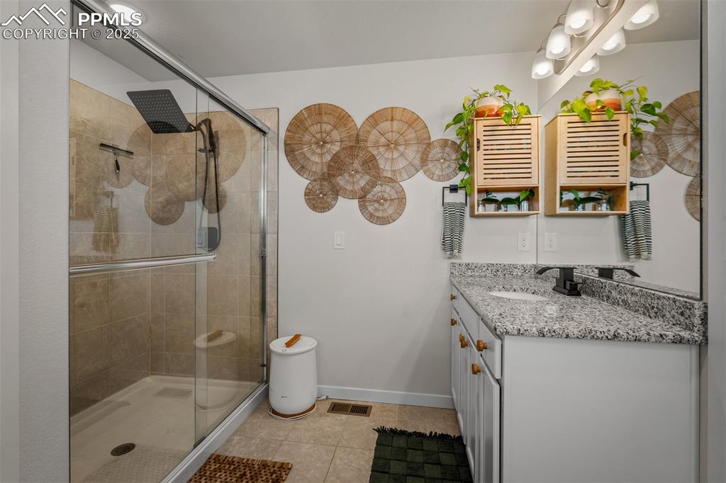 Image 31 of 49: Full bathroom featuring vanity, tile patterned flooring, a stall shower, an