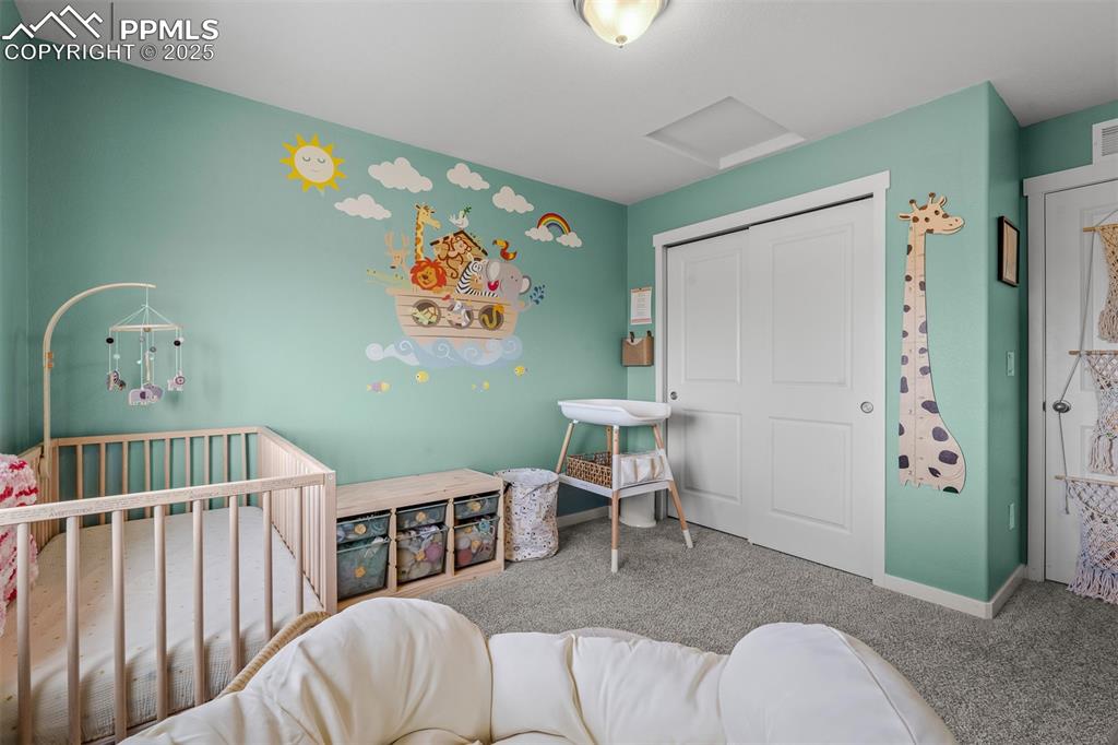 Image 34 of 49: Bedroom featuring carpet flooring, attic access, a nursery area, a closet, 