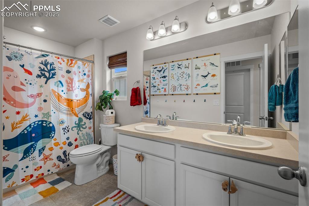 Image 35 of 49: Full bathroom featuring double vanity, toilet, tile patterned floors, and a