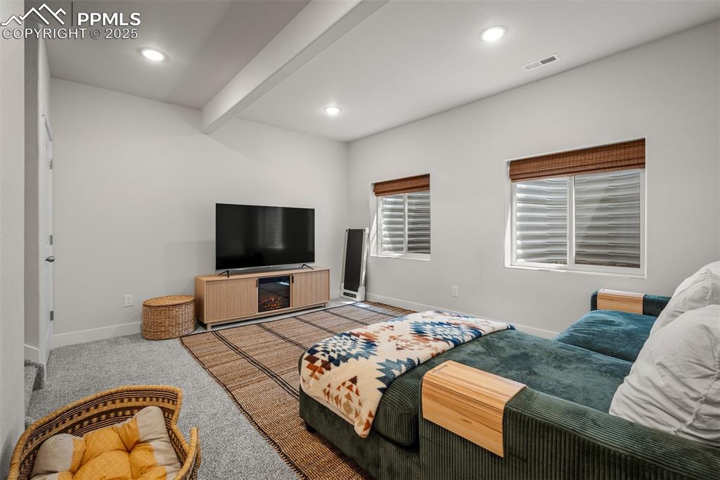 Image 40 of 49: Living area featuring baseboards, beamed ceiling, light colored carpet, and
