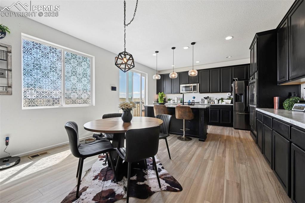 Image 10 of 43: Open-concept kitchen and dining area featuring dark cabinetry with light co