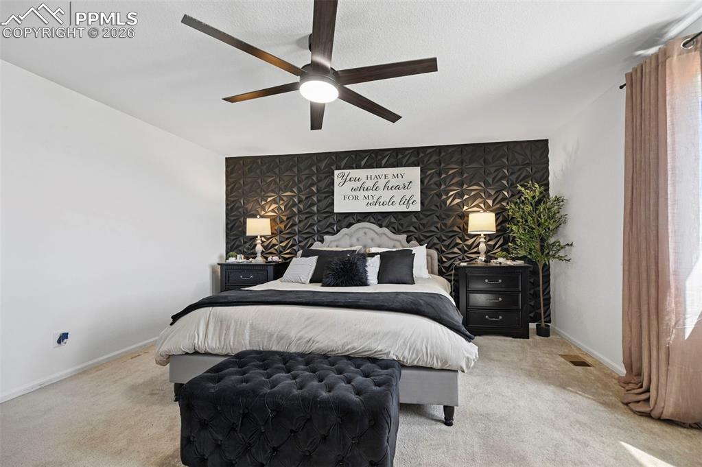 Image 13 of 43: Bedroom featuring a textured accent wall, light-colored carpeting, and a ce
