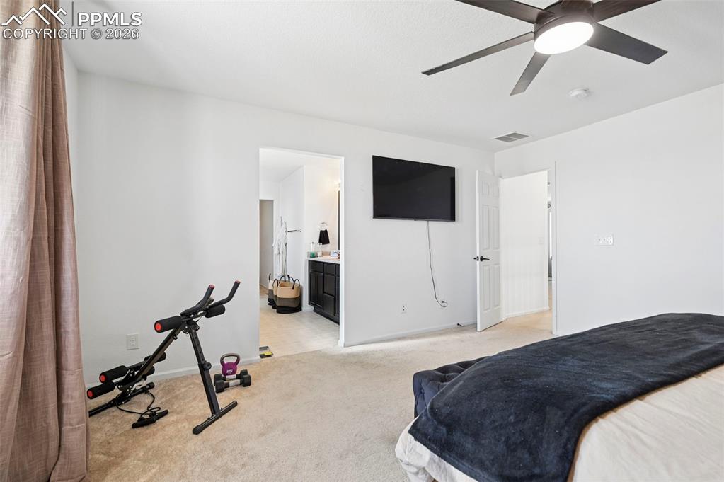 Image 15 of 43: Carpeted bedroom with a ceiling fan and mounted television