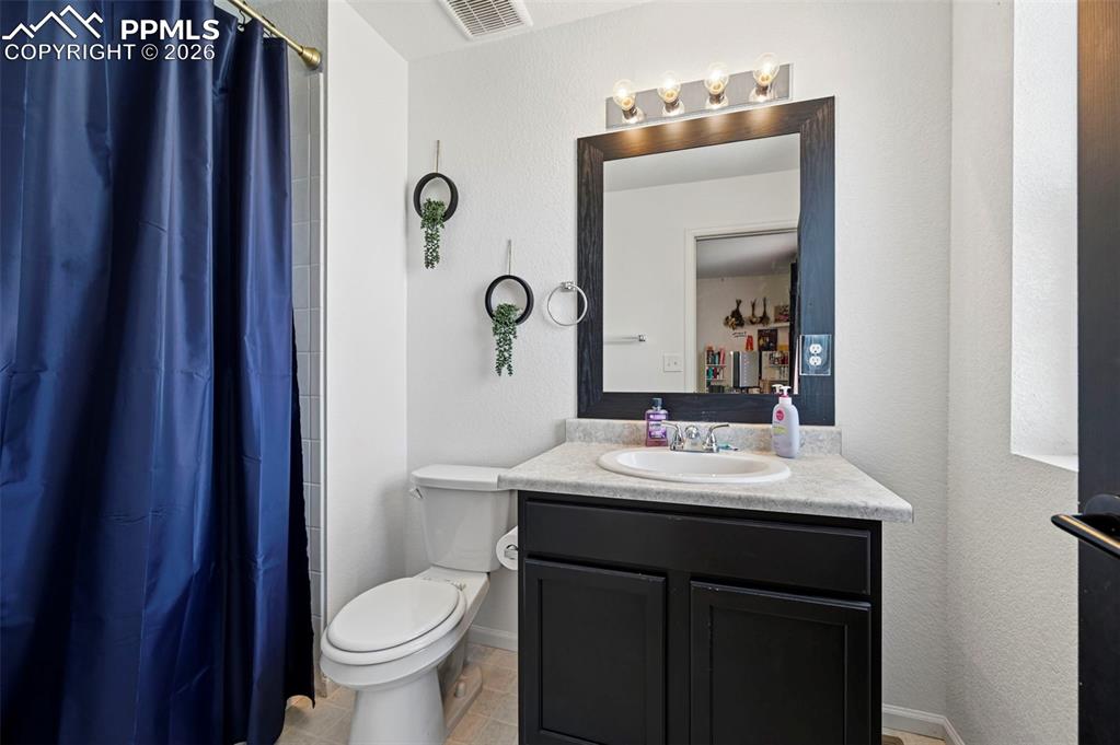 Image 25 of 43: Bathroom featuring a white toilet, black vanity with a light-colored counte