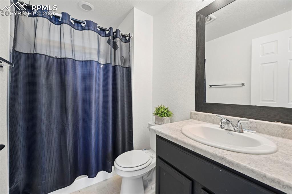 Image 31 of 43: Bathroom featuring a single vanity with an integrated sink, a dark wood-fra