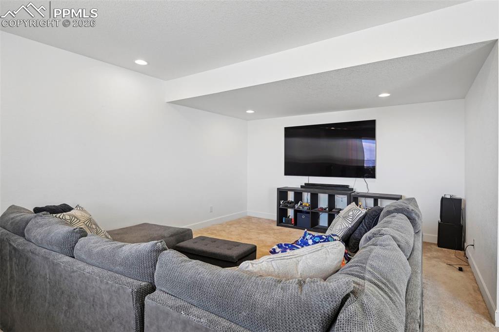 Image 33 of 43: Recessed lighting illuminates a spacious room featuring a wall-mounted disp
