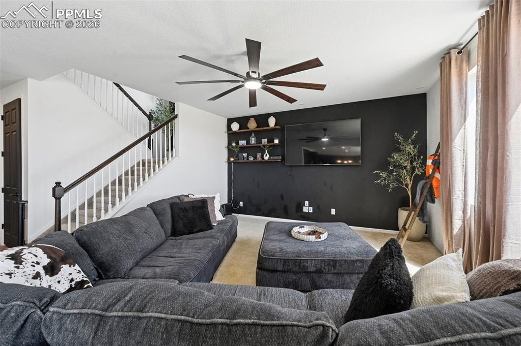 Image 34 of 43: Bright living area featuring a modern ceiling fan with wood-finish blades,