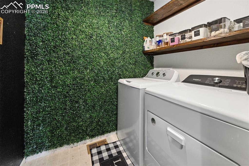 Image 36 of 43: Laundry space featuring a unique green wall texture, white appliances, and
