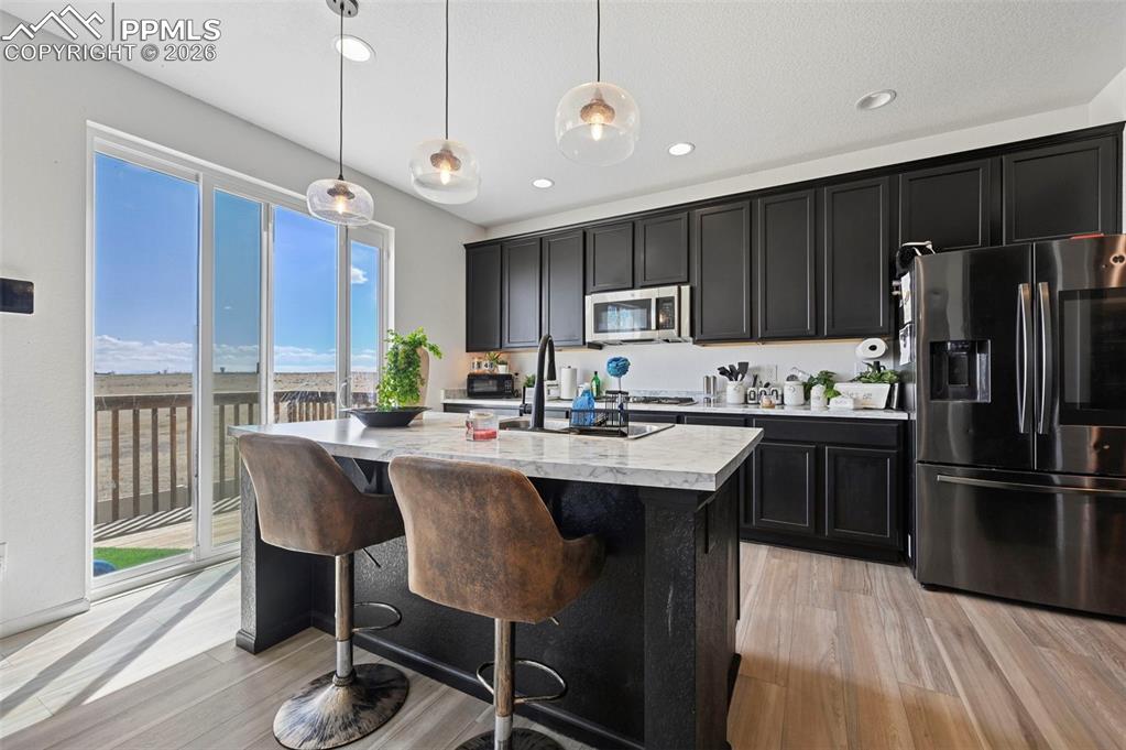 Image 8 of 43: Contemporary kitchen featuring dark cabinetry, stainless steel appliances,