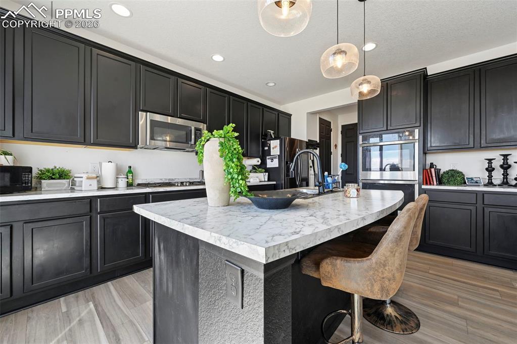 Image 9 of 43: Kitchen featuring dark cabinetry, stainless steel appliances, a center isla