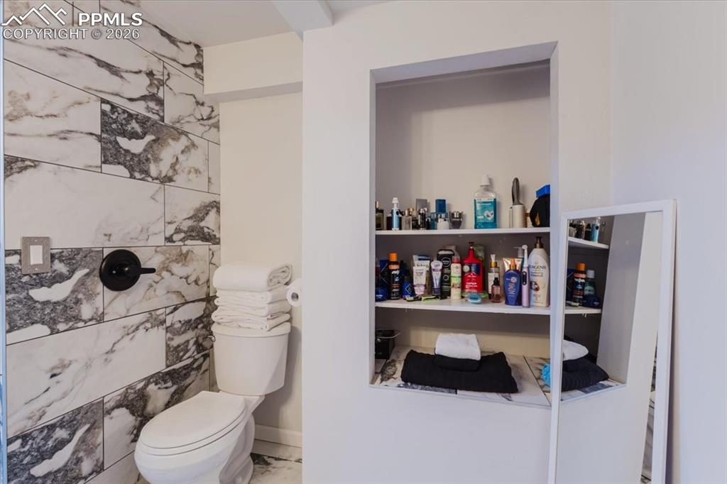 Image 21 of 45: Bathroom featuring large format marble-look tile, matte black fixtures, and