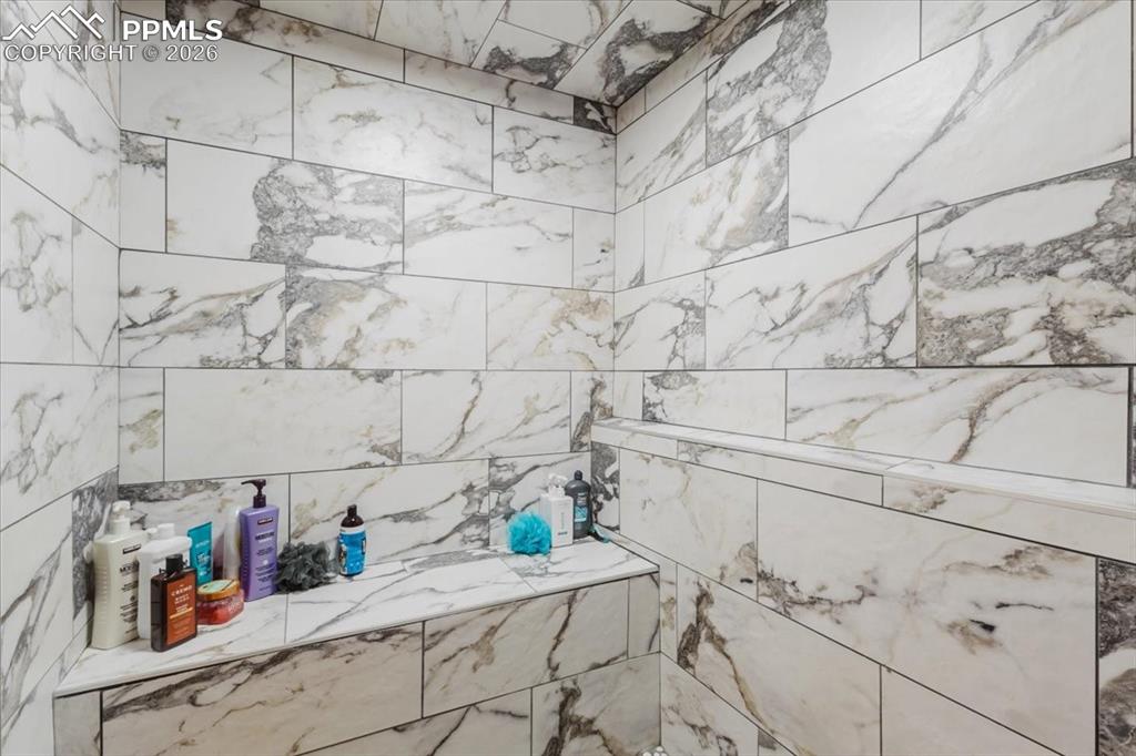Image 23 of 45: Shower enclosure featuring large format tile with natural stone-look veinin