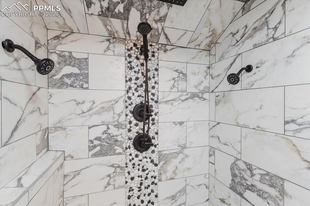 Image 24 of 45: Walk-in shower featuring large format white and gray marble-look tile, a mo