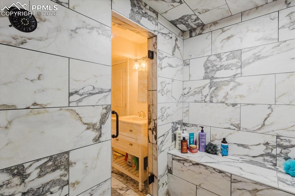 Image 25 of 45: Shower enclosure featuring large format marble-look tile, built-in bench se