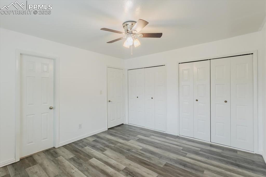 Image 32 of 45: Spacious room featuring wood-finish flooring, white walls, and a ceiling fa