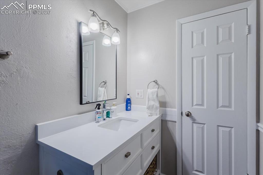 Image 36 of 45: White vanity with integrated sink, contemporary wall-mounted light fixture,