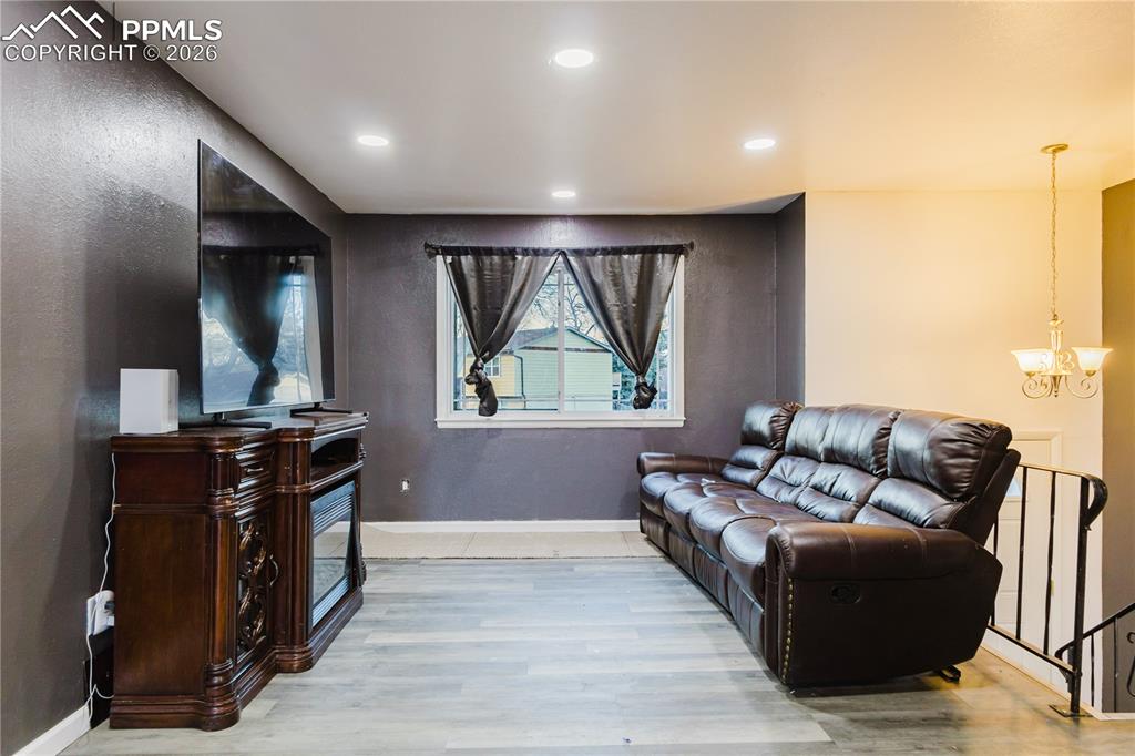 Image 4 of 20: Living room with light wood finished floors and a chandelier