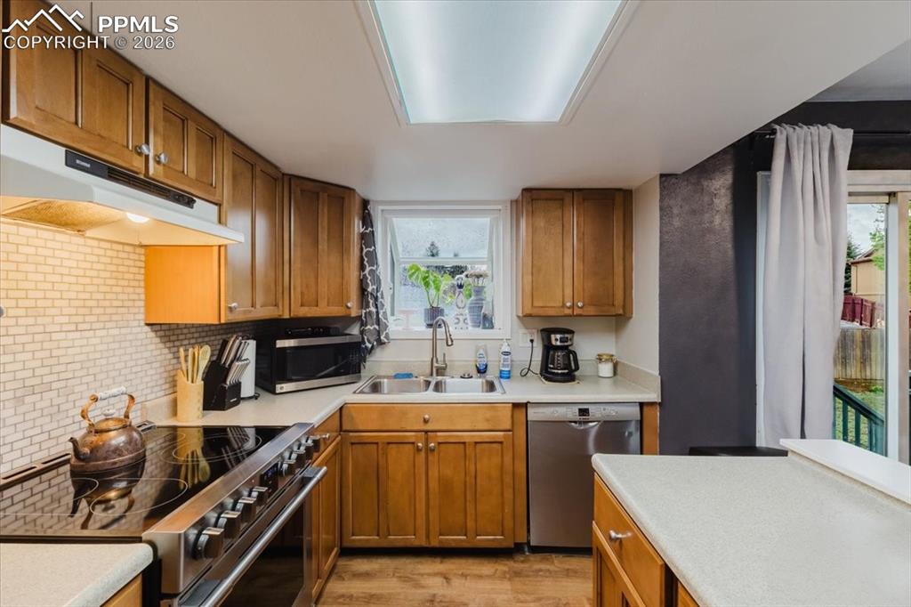 Image 42 of 45: Kitchen featuring wood-finish cabinetry, light-toned countertops, and a whi