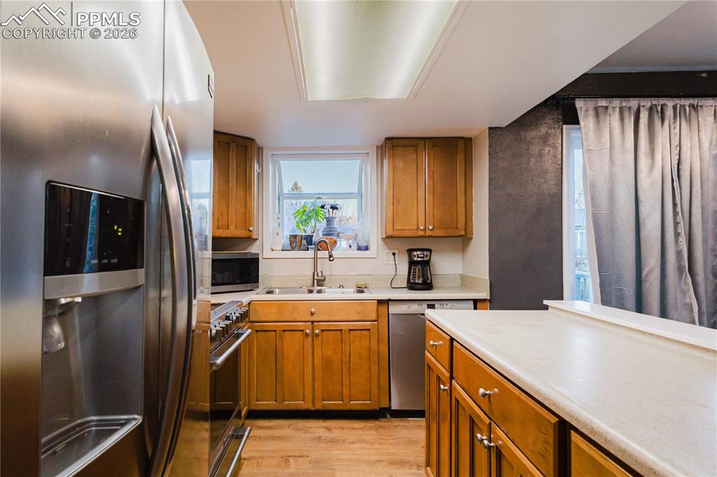 Image 5 of 20: Kitchen with stainless steel appliances, wood finish cabinets, light counte