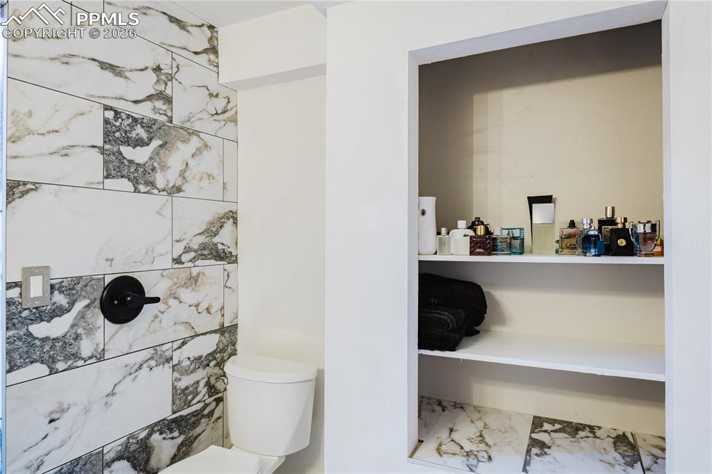 Image 7 of 20: Full bath with toilet and marble look tiles