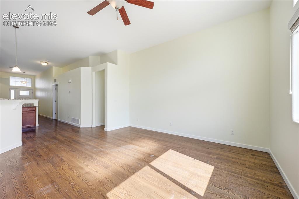 Image 13 of 46: Spacious interior featuring wood-finish flooring, a ceiling fan, and a kitc