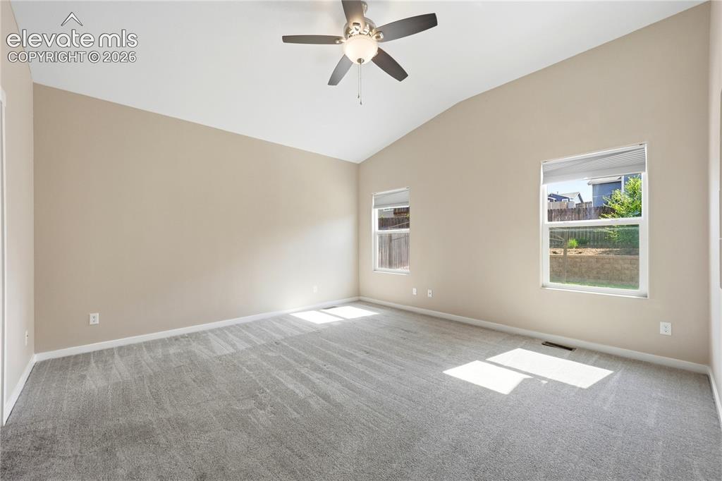 Image 16 of 46: Vaulted ceiling, two windows with roller shades, ceiling fan with integrate