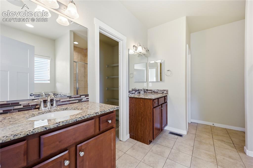 Image 18 of 46: Dual wood-finish vanities with light stone countertops, integrated sinks, a
