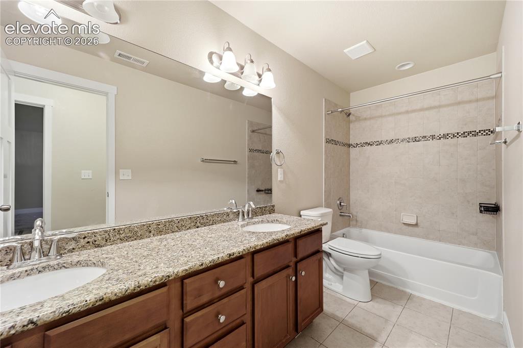 Image 33 of 46: Dual vanity with speckled countertop, wood-finish cabinetry, built-in batht