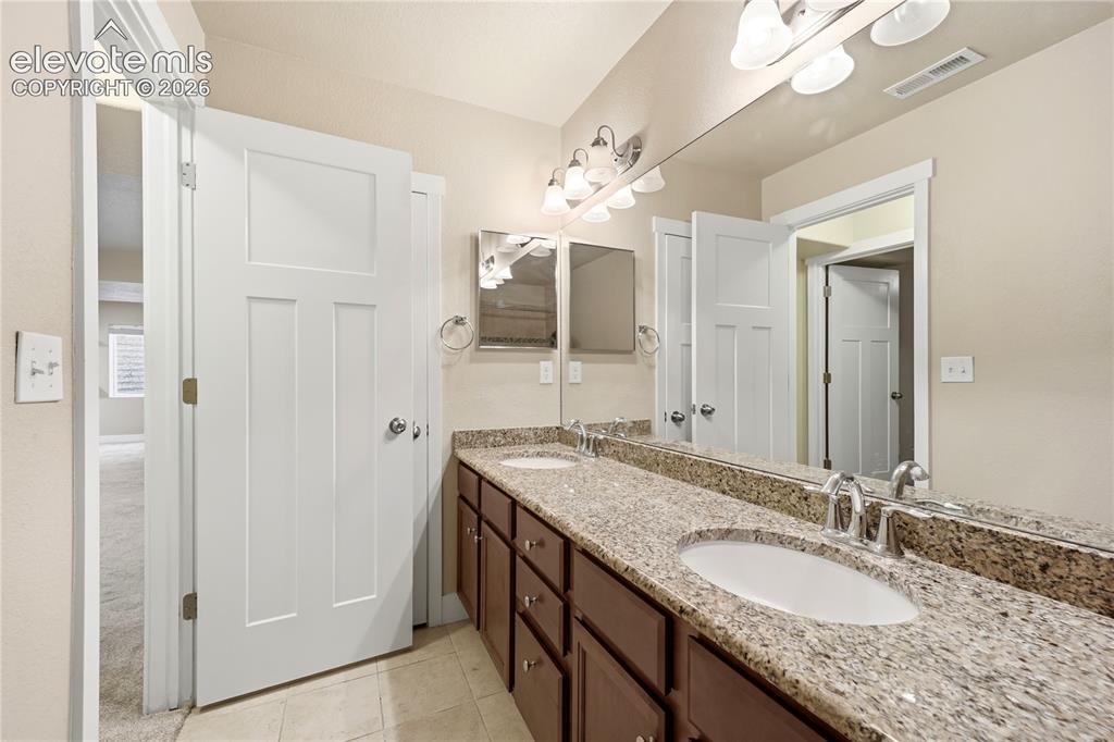 Image 34 of 46: Dual vanity with integrated sinks, granite countertop, brown wood-finish ca