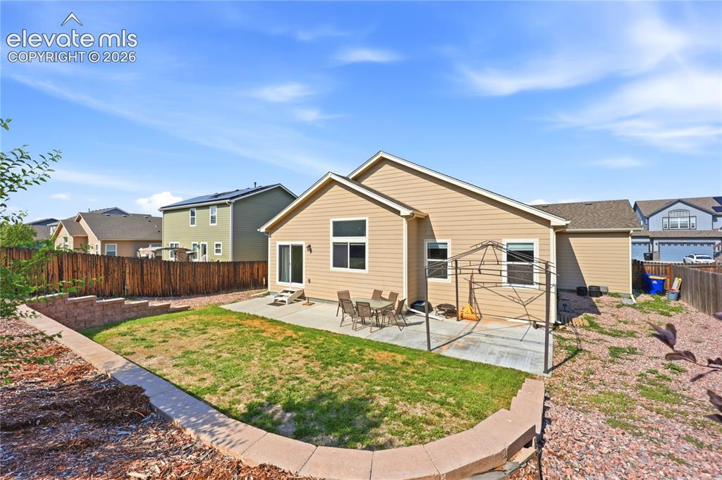 Image 38 of 46: Backyard featuring a concrete patio, wooden privacy fence, and tiered lands