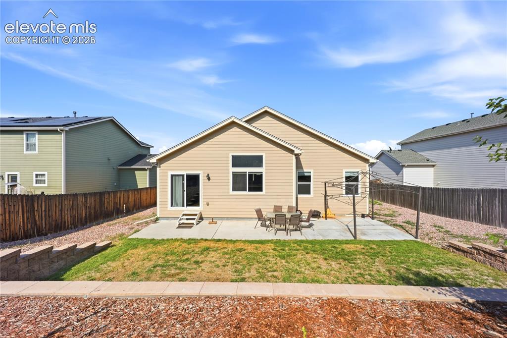 Image 39 of 46: Spacious backyard featuring a concrete patio, sliding glass door access, an
