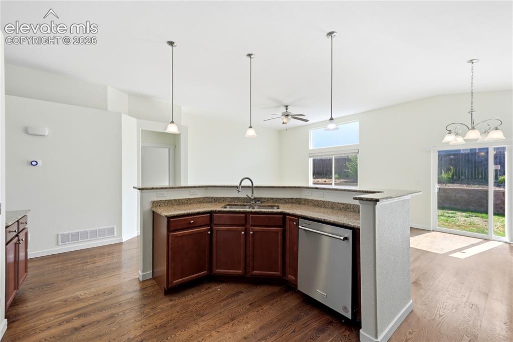 Image 7 of 46: Kitchen with wood-finish flooring, granite countertops, and stainless-steel
