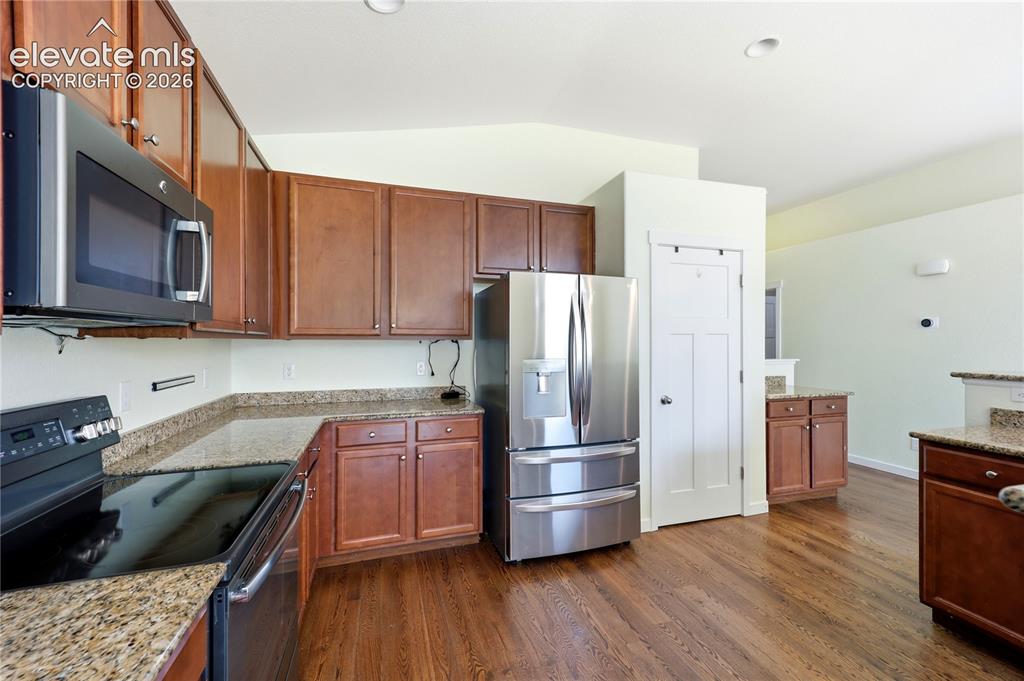 Image 8 of 46: Open-concept living area featuring wood-finish flooring, vaulted ceilings, 