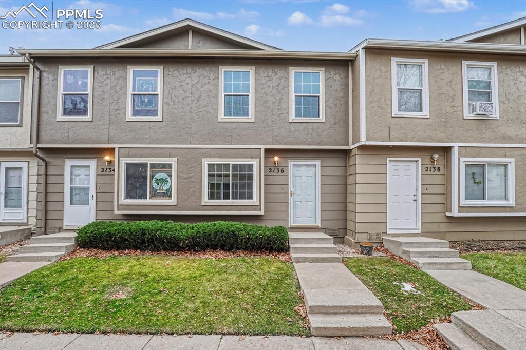 Caption: View of front of home featuring stucco siding, a front lawn, and entry steps