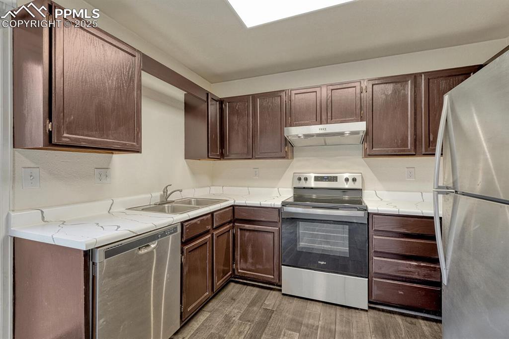 Image 13 of 32: Kitchen with stainless steel appliances, dark brown cabinetry, under cabine