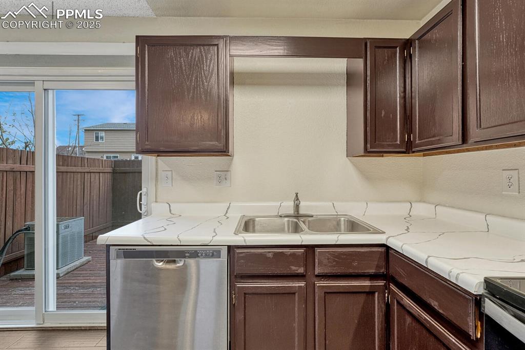 Image 16 of 32: Kitchen featuring dark brown cabinets and stainless steel dishwasher