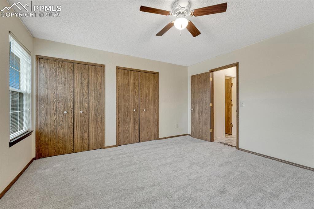 Image 19 of 32: Unfurnished bedroom with multiple closets, a textured ceiling, carpet floor