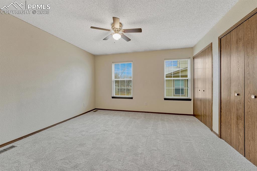 Image 20 of 32: Unfurnished bedroom with multiple closets, carpet floors, a textured ceilin