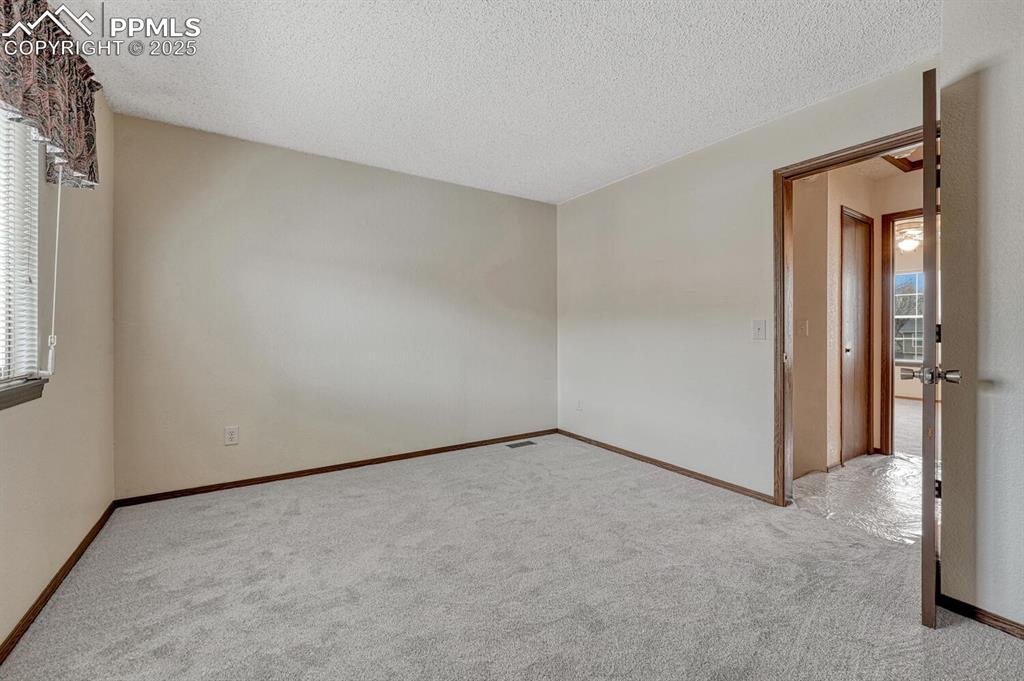 Image 23 of 32: Carpeted empty room featuring a textured ceiling and baseboards