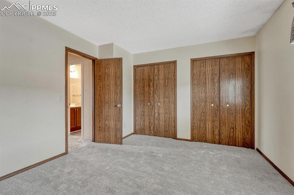 Image 25 of 32: Unfurnished bedroom with two closets, carpet flooring, and a textured ceili