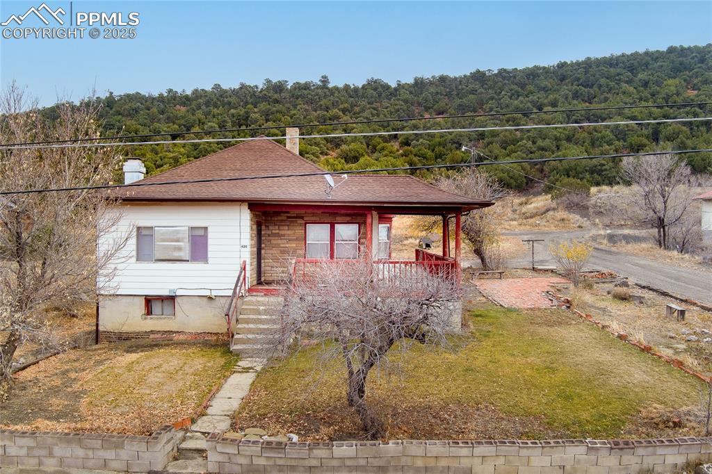 Image 1 of 30: View of front of home featuring a porch, a forest view, a chimney, and a fr