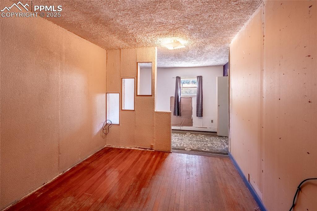 Image 17 of 30: Empty room featuring a textured ceiling, hardwood / wood-style floors, a te