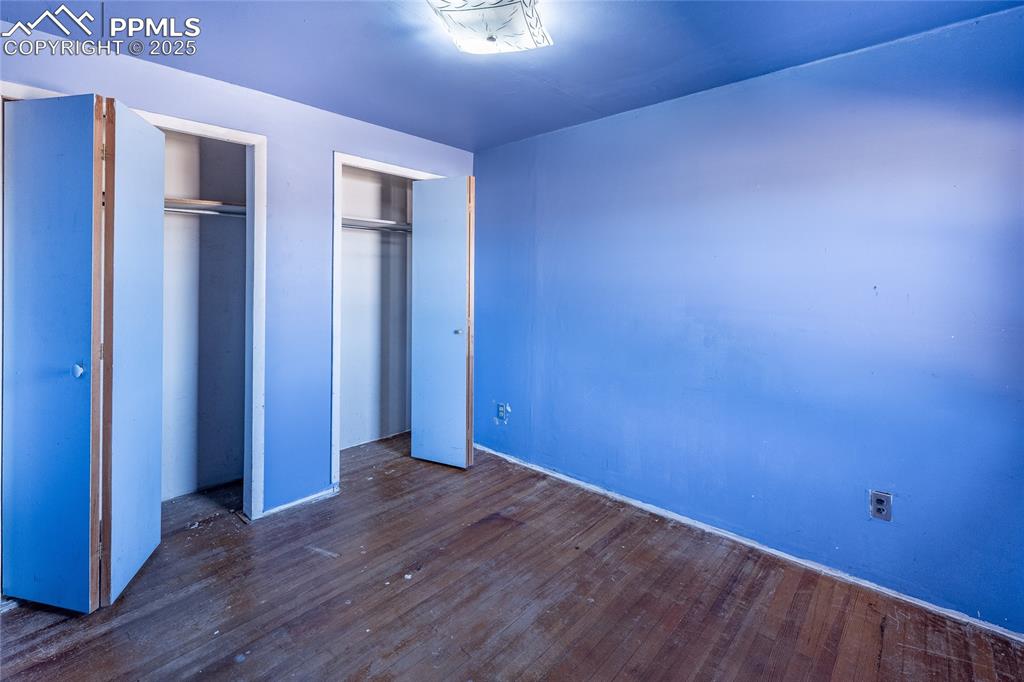Image 18 of 30: Unfurnished bedroom with two closets and dark wood-type flooring
